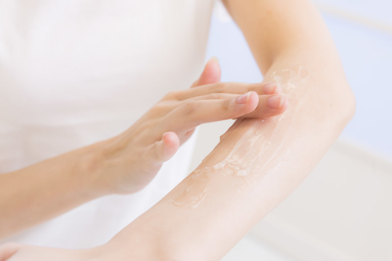 脱毛後の腕の肌をいたわりながら保湿する女性