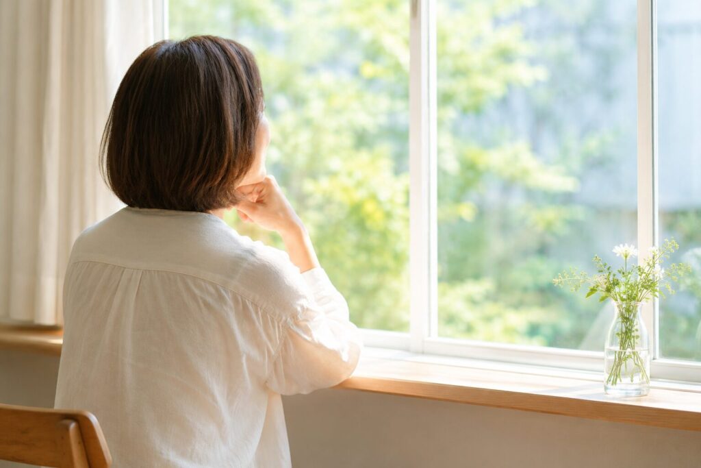 自然光の入る窓辺で穏やかな時間を過ごす女性