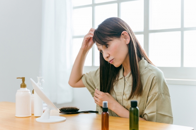 「鏡の前で髪を整える40代女性」