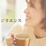 「明るい窓辺で温かい飲み物を持ち、穏やかにほほえむ女性｜病気とレジリエンス・心の回復力」
